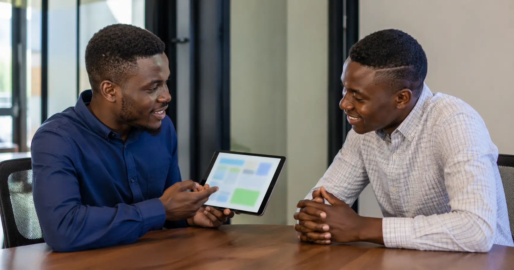 Ghanaian developer and business owner reviewing an app mockup together on a tablet"