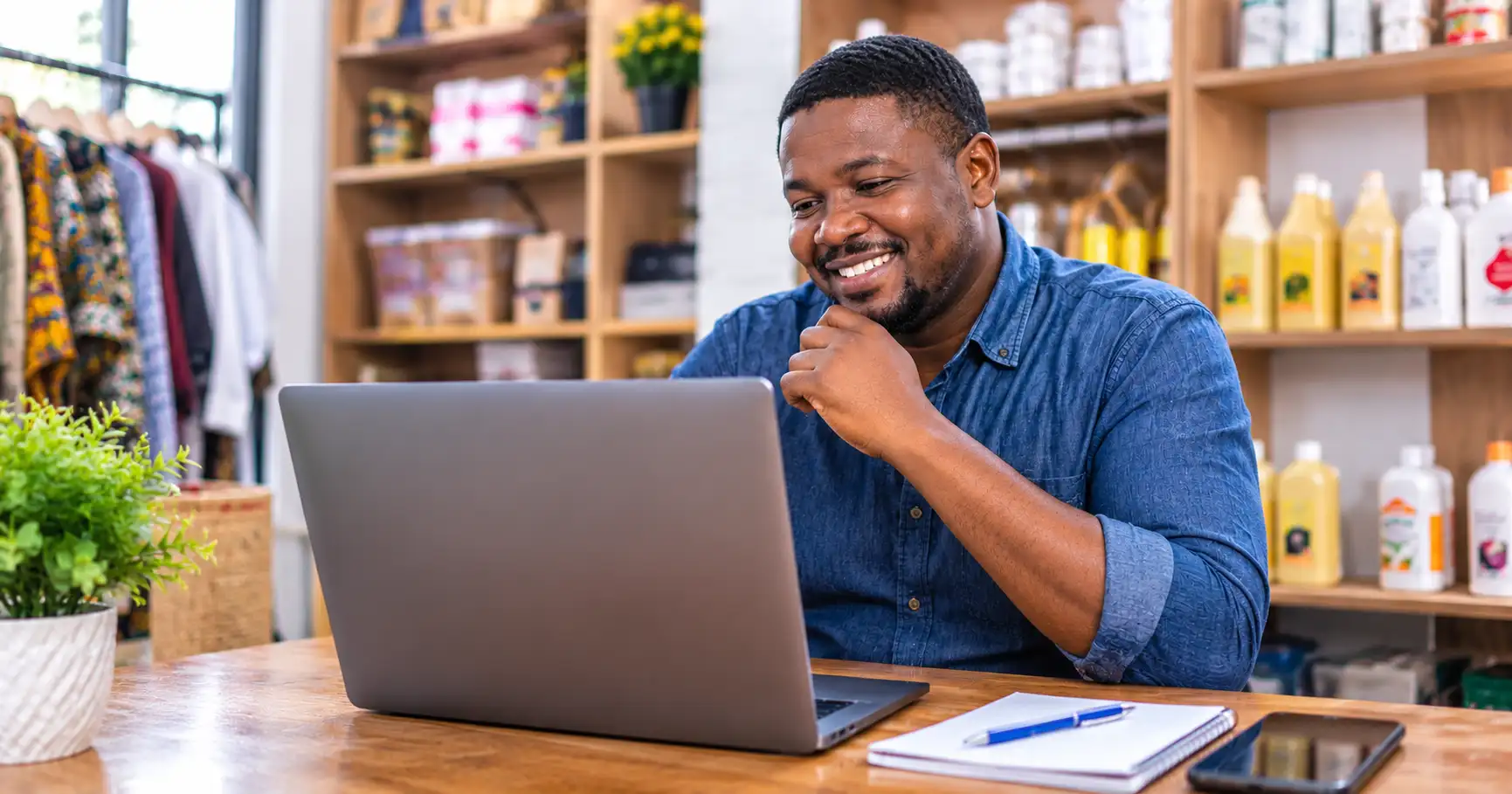 Ghanaian small business owner smiling while reviewing his new website on laptop