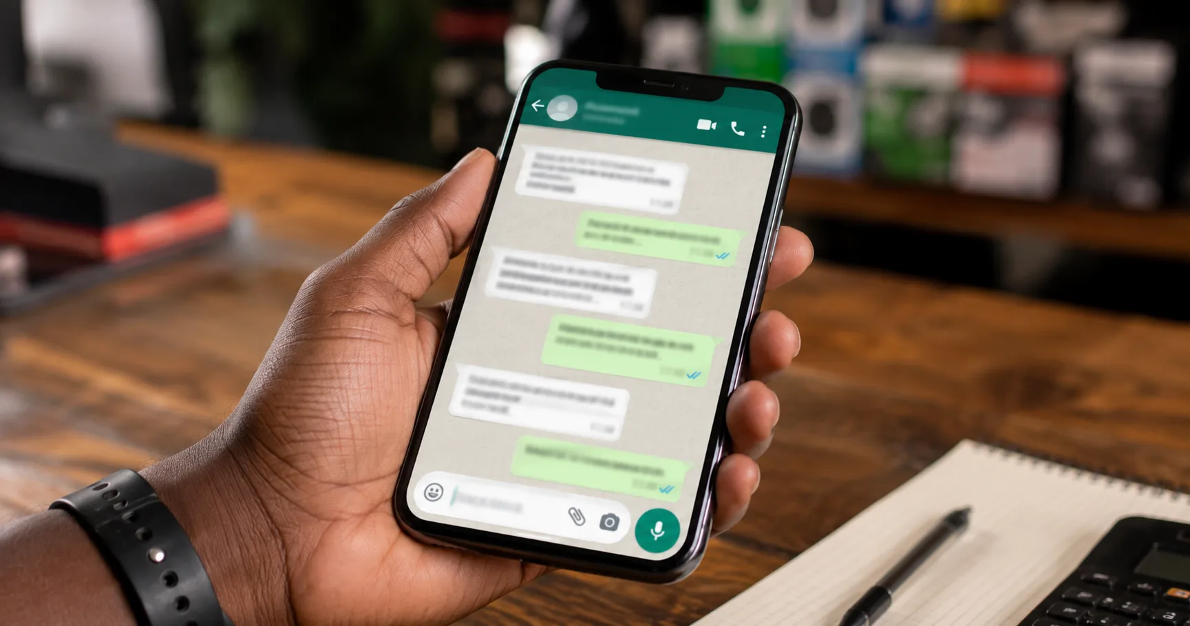 Close-up of hand holding phone with WhatsApp chat conversation on screen