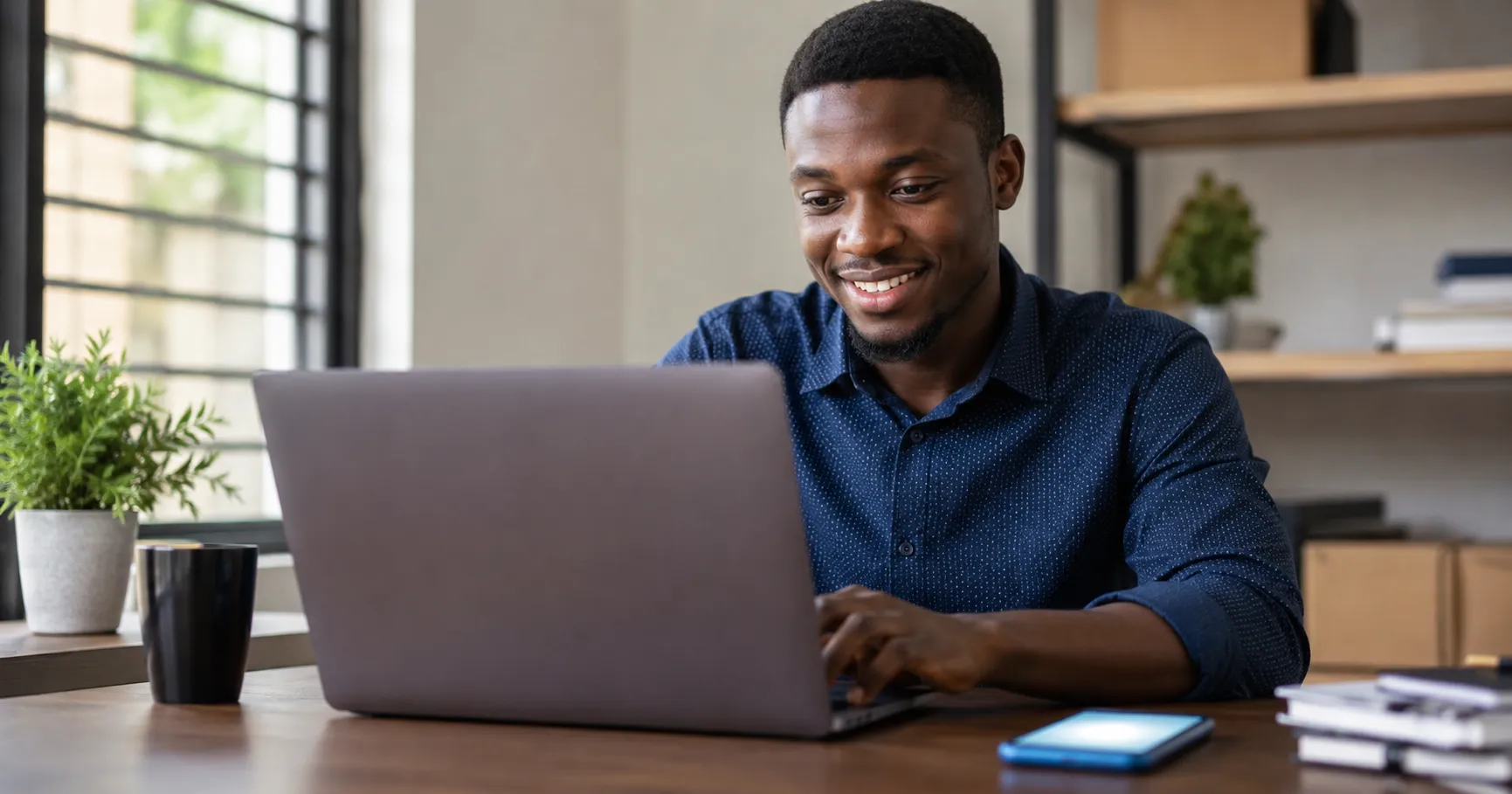 Ghanaian professional smiling while working on laptop with AI tools