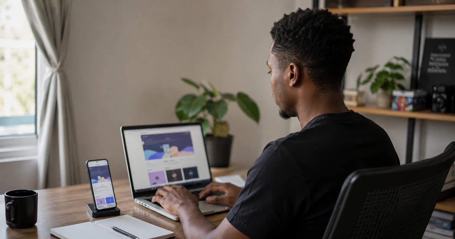 Web developer working on a website design across laptop and phone at desk